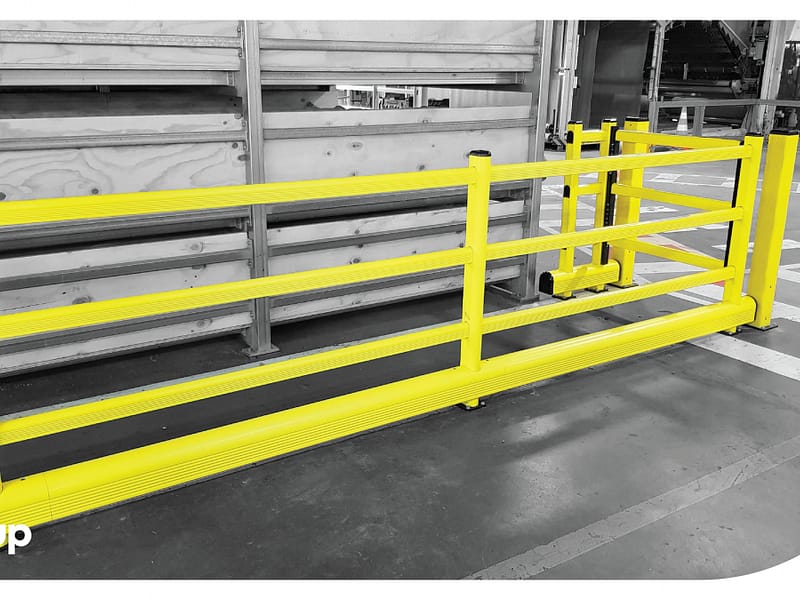 Yellow polymer safety barrier and pedestrian gate in a warehouse.
